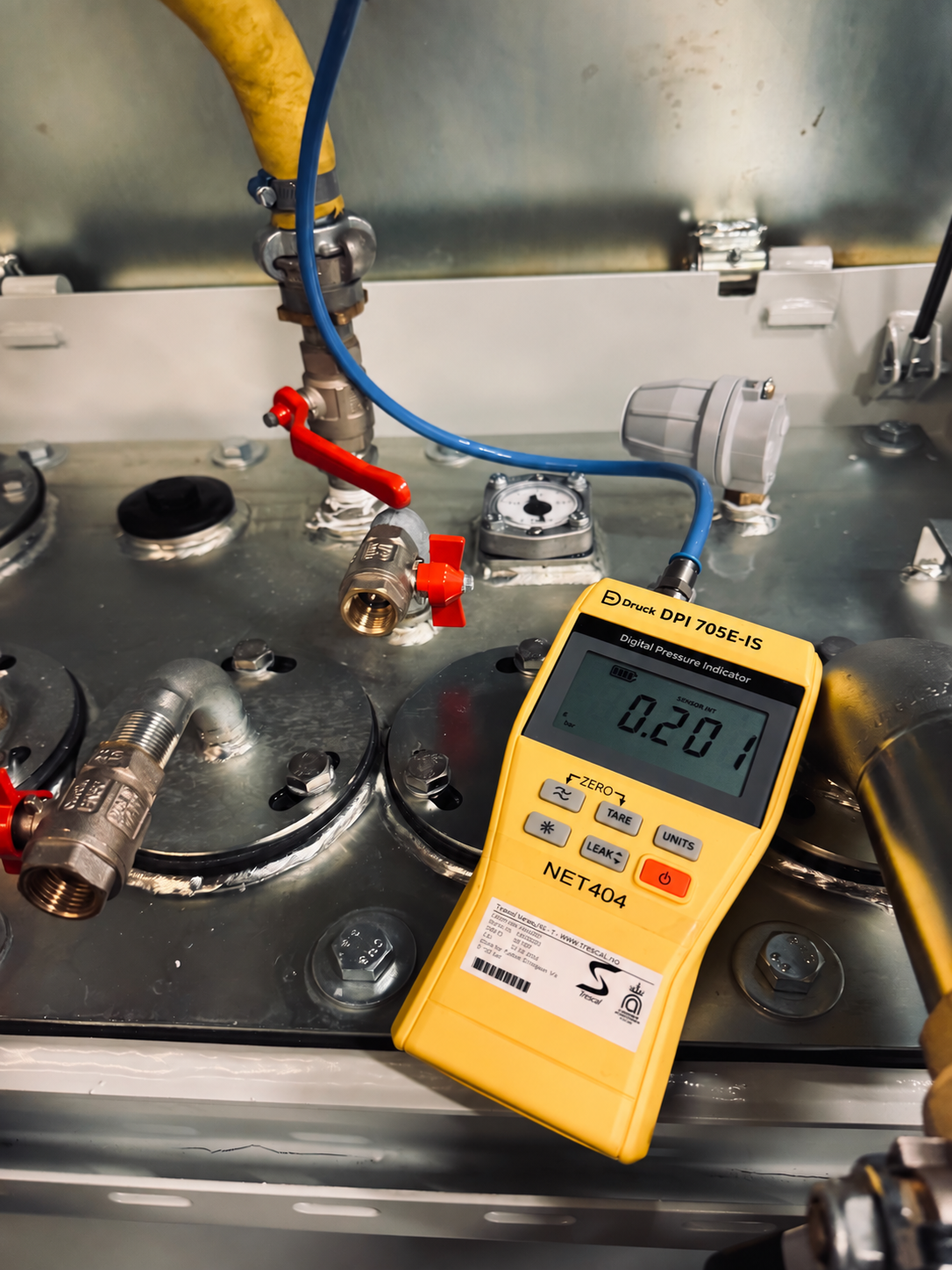 Digital pressure gauge connected to test equipment with hoses and valves